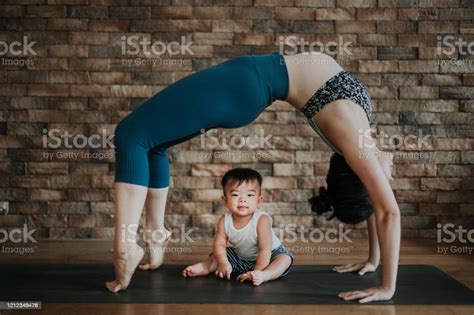 An Asian Chinese Female Yoga Instructor With Bridge Pose While Her Son