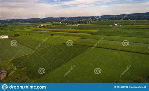 Aerial View Of Farmlands With Barns And Silos Looking Over The Hills