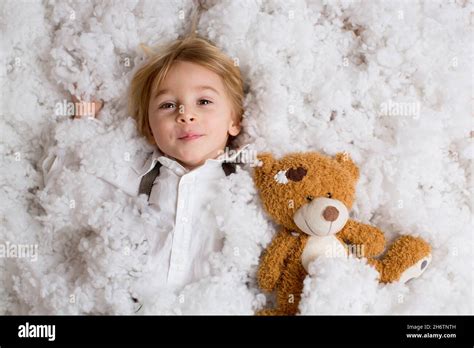 Cute Fashion Toddler Boy Playing In The Snow With Teddy Bear In Front