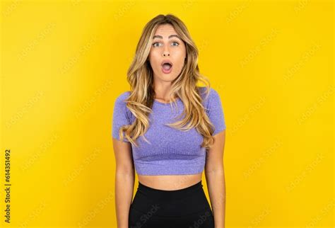 Shocked Young Beautiful Blonde Woman Wearing Sportswear Over Yellow