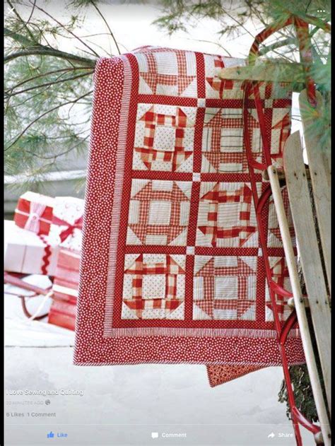A Red And White Quilt Hanging From A Tree In The Snow Next To A Sled