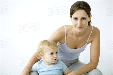Woman Smiling At Camera Toddler Standing Between Legs Stock Photo