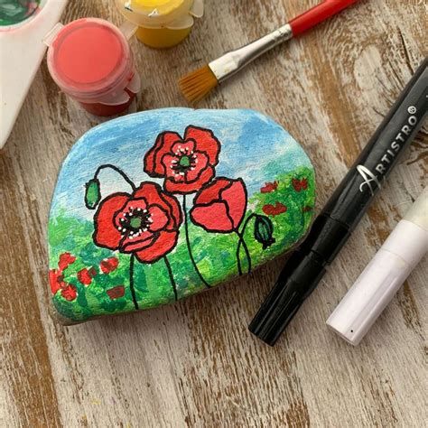 A Rock With Flowers Painted On It Next To Some Paint And Brushes