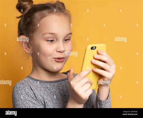 Attractive Little Blonde Girl Looking At Her Mobile Phone Screen With