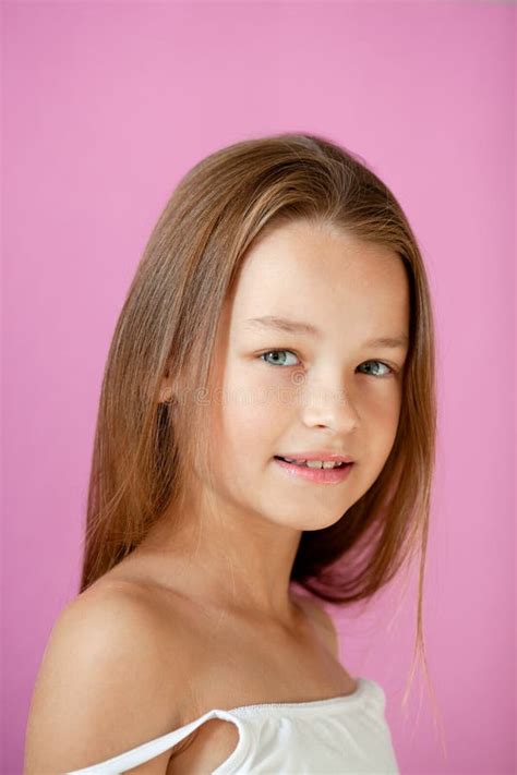 Portrait Of A Gentle 9 Year Old Long Haired Girl In A Light T Shirt Against A Lilac Wall Stock