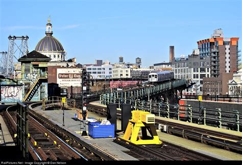 A Queens-bound J train passes between both old and new architecture as ...