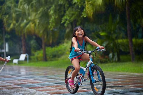 little asian girl riding bike in the park by stocksy contributor bo bo stocksy