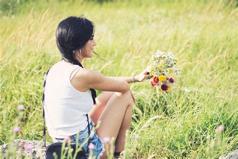 Young Girl Sitting In Field With Wildflower Bouquet In Her Hands By Stocksy Contributor
