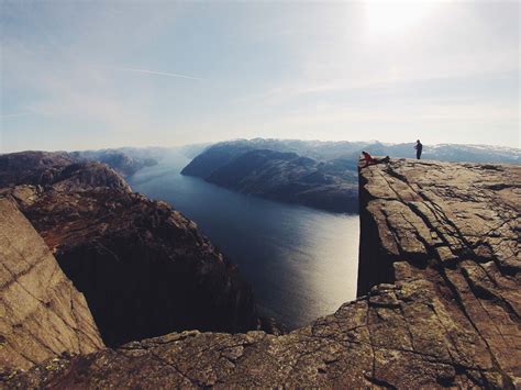 Person Standing At The Edge Of A Cliff Overlooking River Surrounded By