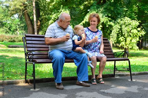 Grandmother Grandfather And Granddaughter Are Sitting On A Bench And