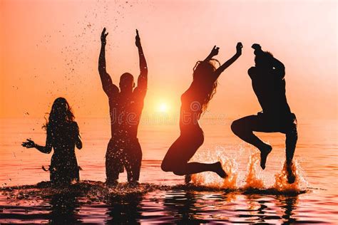 Happy Friends Jumping Inside Water On Tropical Beach At Sunset Group