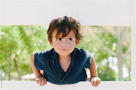 Cute Toddler Boy Looks Up Through A Fence Del Colaborador De Stocksy