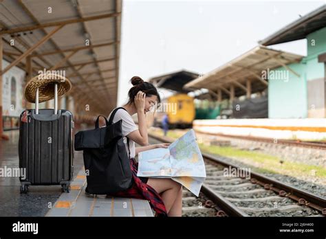 Young Woman Traveler With Backpack Looking To Map While Waiting For Train Asian Backpacker On