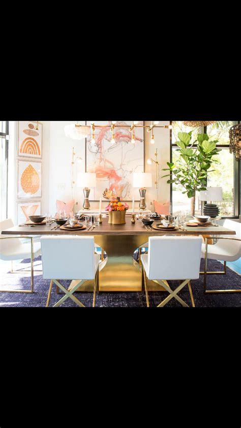 The Dining Room Table Is Set With White Chairs And Gold Accents Along