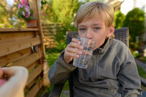 Young Handsome Boy Drinking Water In The Backyard Stock Photo