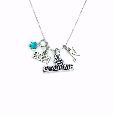 A Necklace With The Words Graduate On It And Charms Hanging From Its Sides