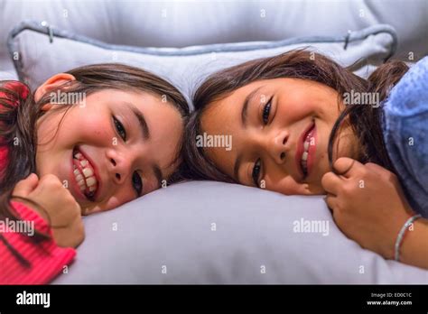 Portrait Of Two Smiling Girls Lying On A Bed Stock Photo Alamy