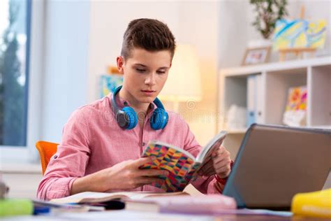 Teenager Wearing Earphones On Neck Sitting At The Laptop And Studying