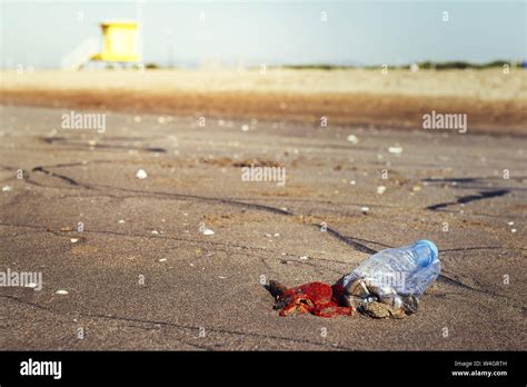 Plastic Bottle And Trash Lies On The Sand Of The Beach And Pollutes The