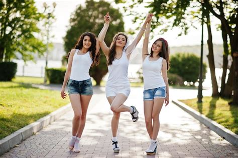 premium photo three happy and sexy girls on short shorts and white shirts posed on road at