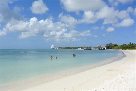 Some People Are Swimming In The Clear Blue Water On A Beach With White