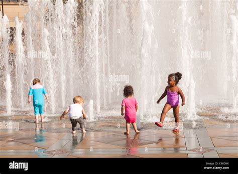 Children Playing In The Fountains And Enjoying The Sunshine In The