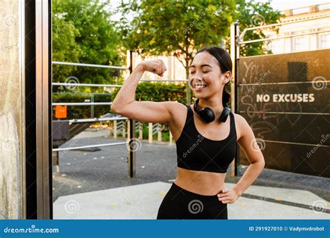 Young Asian Woman Smiling And Showing Her Bicep On Playground Stock
