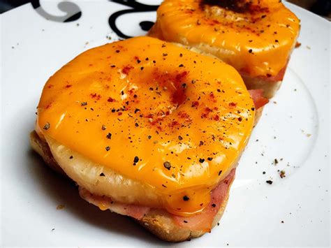 Two donuts covered in cheese and ham on a plate