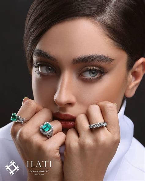 A Woman Is Posing With Her Hands On Her Face And Wearing Two Rings One