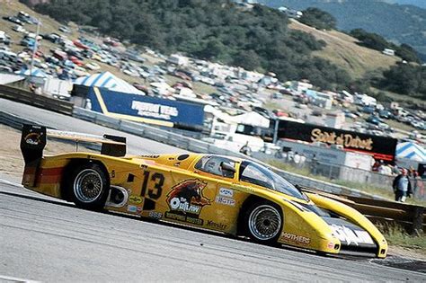 A Yellow Race Car Driving Around A Track