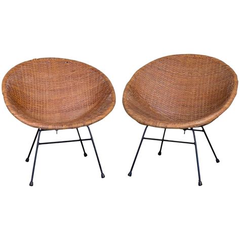 The beauty of rattan is in the sculptural quality of the form, exemplified in this simple and light form that is supported by the steel frame of the four black legs. Pair of Mid-Century Rattan Scoop Chairs at 1stdibs