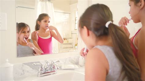 Two Cute Little Sisters Share The Bathroom While They Brush Their Teeth