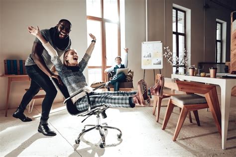 los trabajadores de oficina se divierten compitiendo en sillas de oficina foto premium