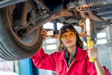 Woman Mechanic Examining Under The Car At The Repair Garage Stock Image