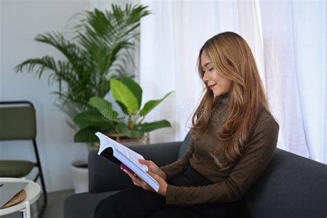 Asian Woman Relaxing In Living Room And Reading Book Stock Image