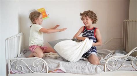 the brother and the sister have arranged fight by pillows on a bed in a bedroom the naughty