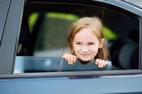 A Little Girl Is Sticking Her Head Out The Car Window Stock Photo