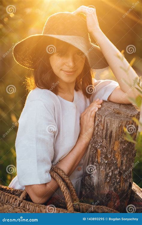 Stylish Girl In Linen Dress Holding Rustic Straw Basket At Wooden Fence