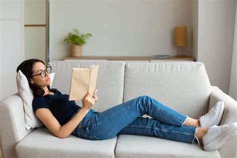 Student Girl Reading Book Studying Lying On Couch At Home Stock Image