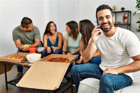 grupo de jóvenes amigos hispanos comiendo pizza italiana sentados en el sofá foto de archivo