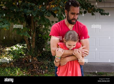 Father Embracing Daughter While Standing At Yard Stock Photo Alamy