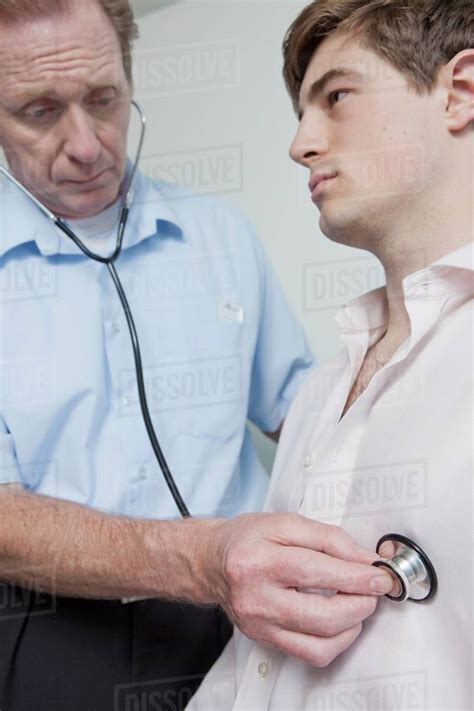 Doctor Using Stethoscope On Patient During Medical Examination Stock