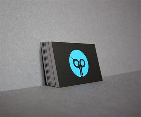 A Black And Blue Business Card Sitting On Top Of A Gray Table Next To A