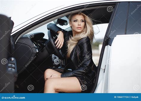 Stylish Young Woman With Long Blond Hair Sitting On The Driver`s Seat Of A Prestigious Car Stock