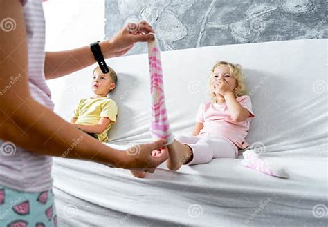 Mom Takes Off Her Little Daughter`s Socks And Tickles Her Feet A Little The Girl Laughs Stock