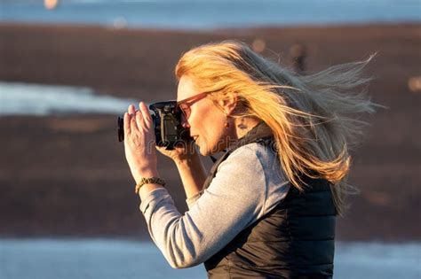 A Woman With A Dslr Takes An Outdoor Picture On A Windy Sunset Evening