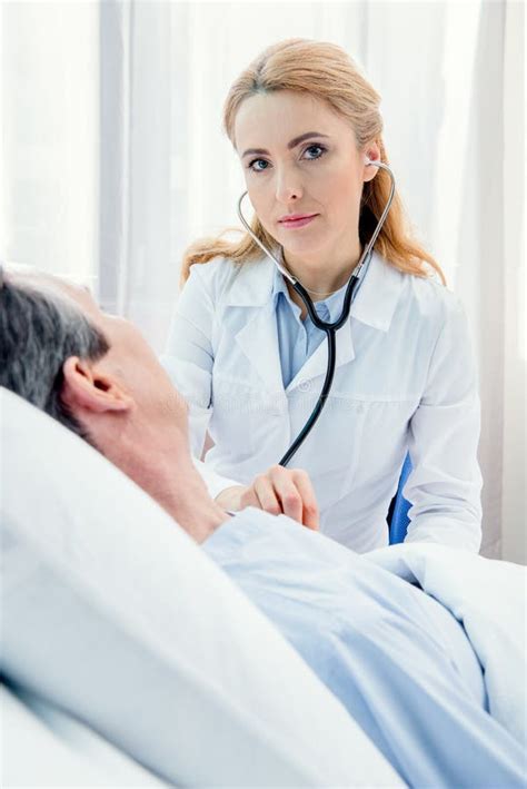 Middle Aged Patient Lying On Bed And Doctor Examining Him With