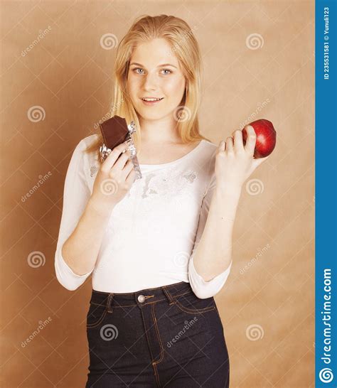 Young Beauty Blond Teenage Girl Eating Chocolate Smiling Choice Between Sweet And Apple Stock