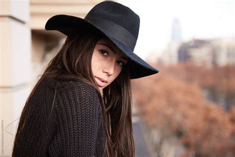 Young Woman In Black Hat Looking At Camera Over Her