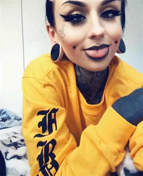 a woman with black makeup and piercings on her face